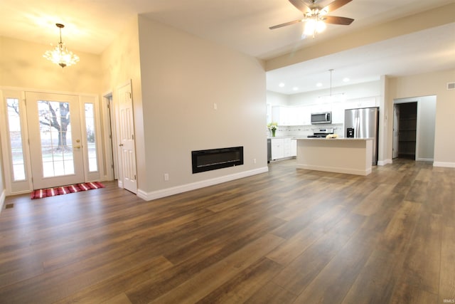 unfurnished living room with ceiling fan with notable chandelier and dark hardwood / wood-style floors