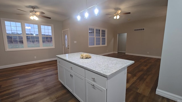 kitchen with dark wood-type flooring, white cabinets, hanging light fixtures, ceiling fan, and a kitchen island