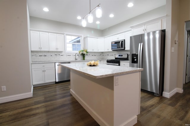 kitchen featuring pendant lighting, a center island, dark wood-type flooring, appliances with stainless steel finishes, and white cabinetry