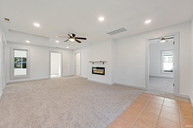 unfurnished living room with light carpet, plenty of natural light, and ceiling fan