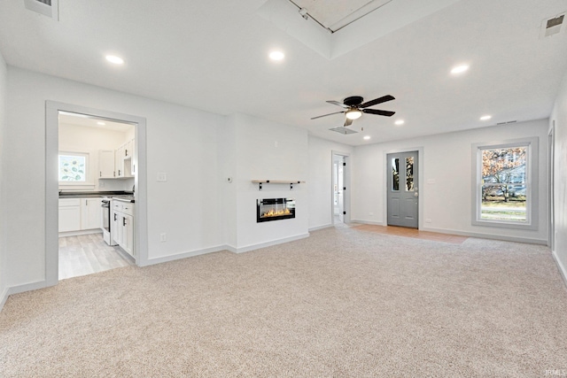 unfurnished living room featuring ceiling fan and light carpet