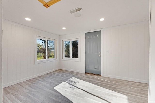 unfurnished room featuring light wood-type flooring and wooden walls