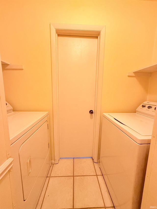 clothes washing area with light tile patterned floors and washing machine and clothes dryer