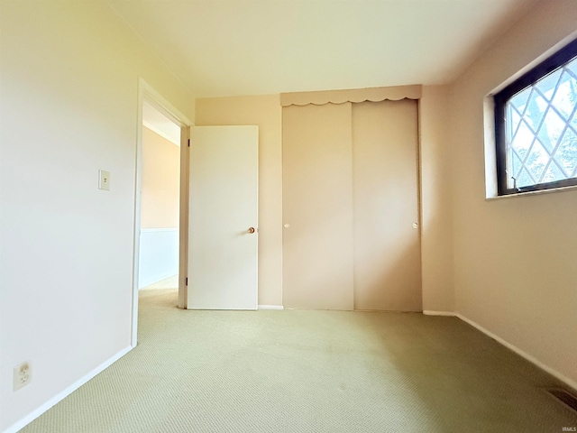 unfurnished bedroom featuring light colored carpet and a closet