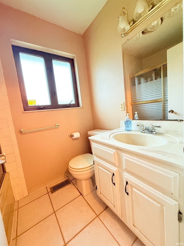 bathroom featuring toilet, tile patterned flooring, vanity, and walk in shower