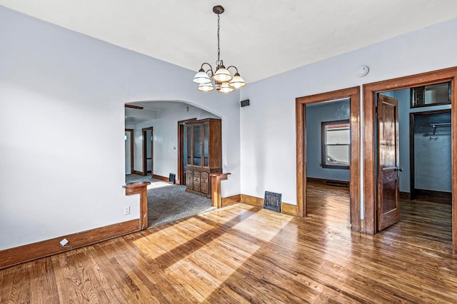 unfurnished room with hardwood / wood-style floors and an inviting chandelier