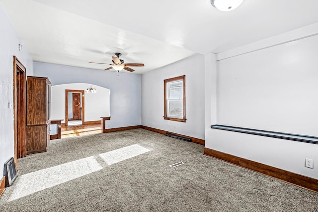 carpeted spare room with ceiling fan with notable chandelier