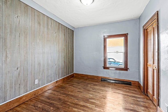 unfurnished bedroom with dark hardwood / wood-style flooring and wooden walls