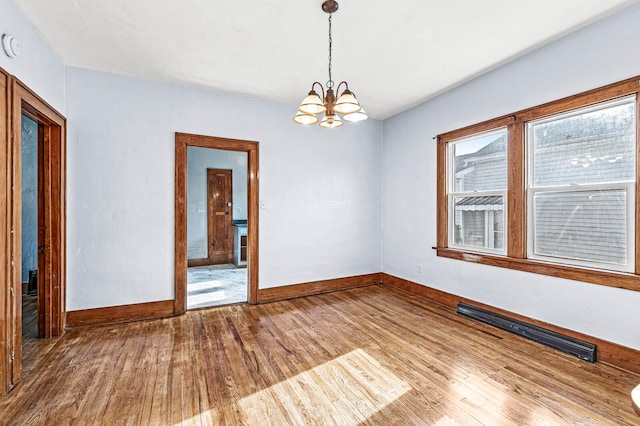 empty room with a notable chandelier and hardwood / wood-style flooring