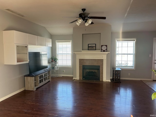 unfurnished living room with ceiling fan, dark hardwood / wood-style flooring, a tiled fireplace, and vaulted ceiling