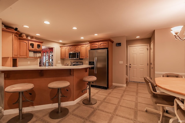 kitchen with a kitchen bar, kitchen peninsula, stainless steel appliances, sink, and a chandelier