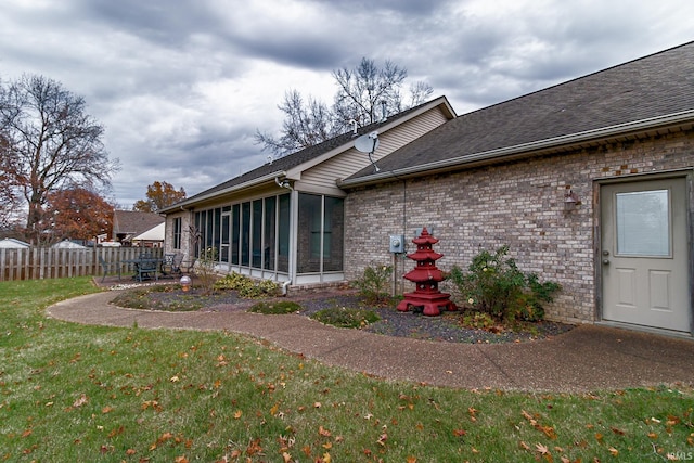 rear view of property featuring a yard and a sunroom