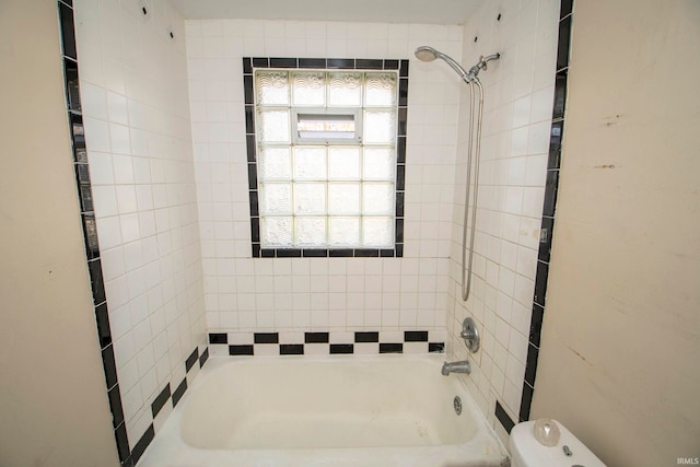 bathroom with toilet and tiled shower / bath