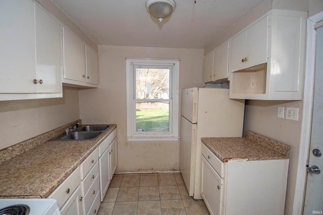 kitchen with white cabinets, light tile patterned floors, white refrigerator, and sink