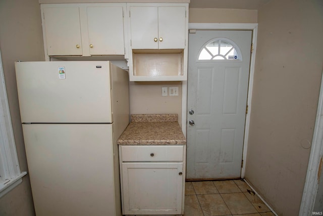 kitchen featuring light tile patterned floors, white fridge, and white cabinetry