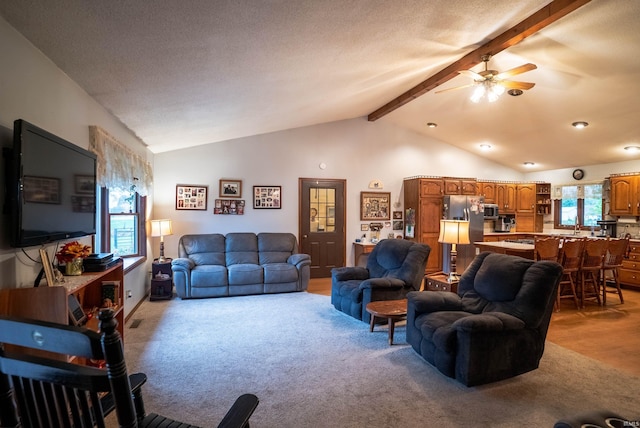 living room with light carpet, a textured ceiling, lofted ceiling with beams, and ceiling fan