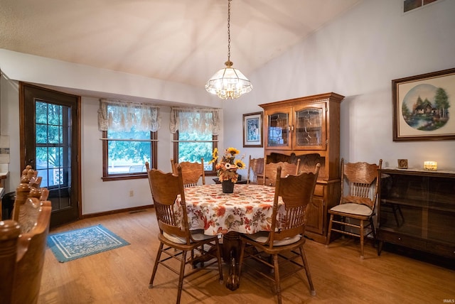 dining room with light wood-type flooring, lofted ceiling, and a notable chandelier