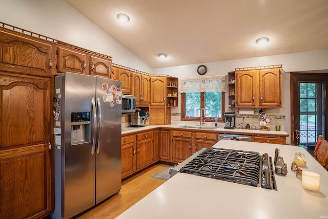 kitchen with sink, tasteful backsplash, light hardwood / wood-style flooring, lofted ceiling, and appliances with stainless steel finishes