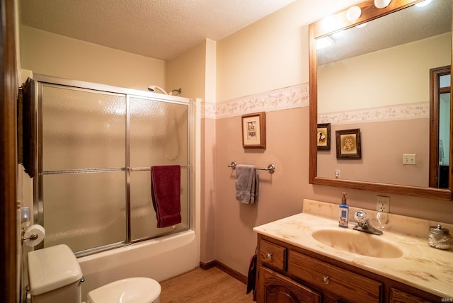 full bathroom with enclosed tub / shower combo, hardwood / wood-style floors, a textured ceiling, toilet, and vanity