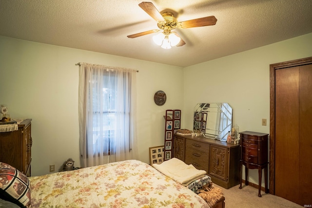 bedroom featuring ceiling fan, light colored carpet, and a textured ceiling