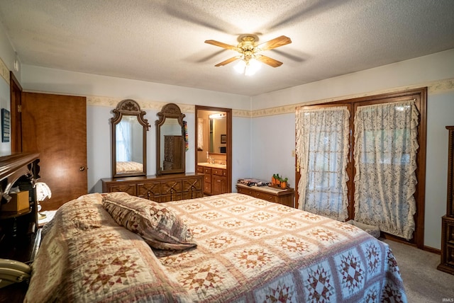 carpeted bedroom with ceiling fan, ensuite bathroom, and a textured ceiling