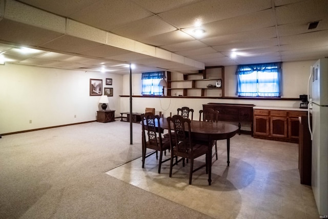 carpeted dining area featuring a drop ceiling