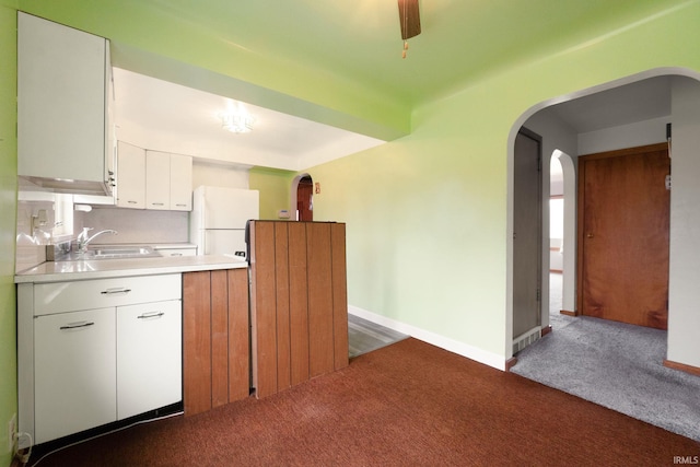 kitchen with sink, white cabinets, white fridge, and dark carpet