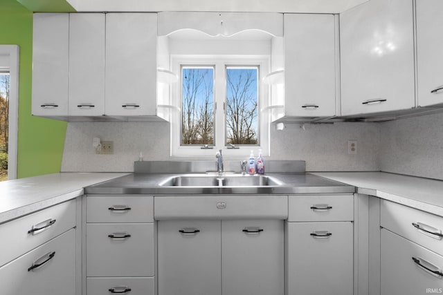 kitchen featuring decorative backsplash, white cabinetry, and sink