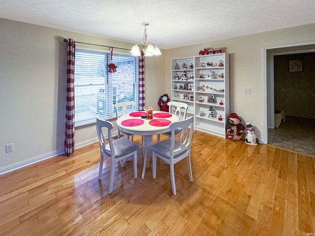 dining area featuring an inviting chandelier, a textured ceiling, and hardwood / wood-style flooring