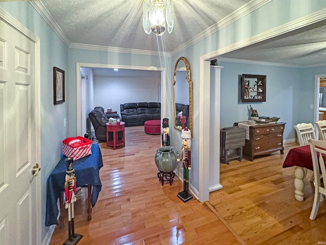 hall featuring wood-type flooring, a textured ceiling, and ornamental molding