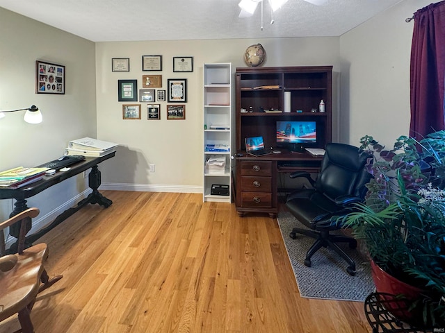 office featuring a textured ceiling, light wood-type flooring, and ceiling fan