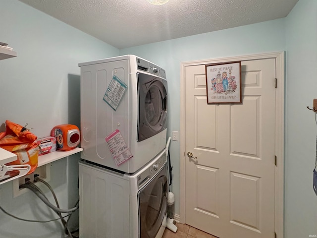 laundry area with stacked washer and dryer, light tile patterned flooring, and a textured ceiling