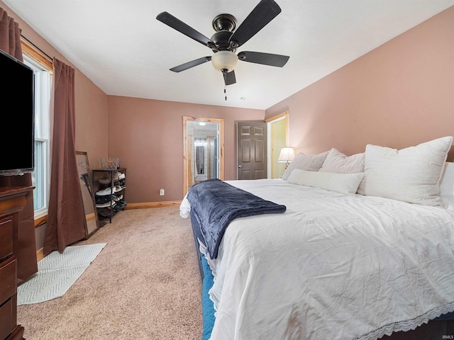 bedroom with ceiling fan, light colored carpet, and ensuite bathroom