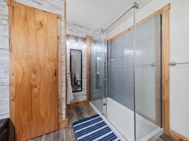 bathroom with an enclosed shower and wood-type flooring