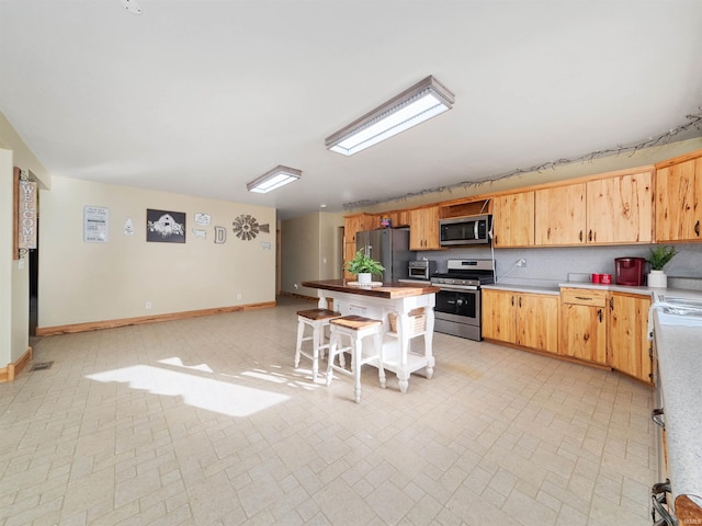 kitchen with a center island, a kitchen bar, backsplash, and appliances with stainless steel finishes