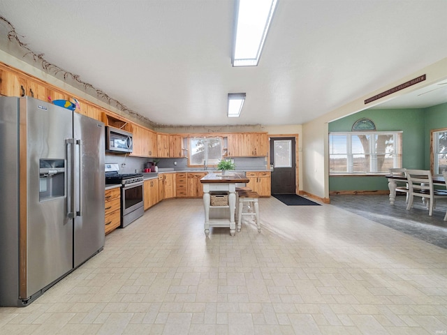 kitchen with a kitchen island, sink, stainless steel appliances, and a breakfast bar area