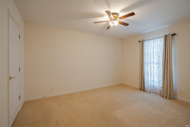 spare room with ceiling fan and light colored carpet