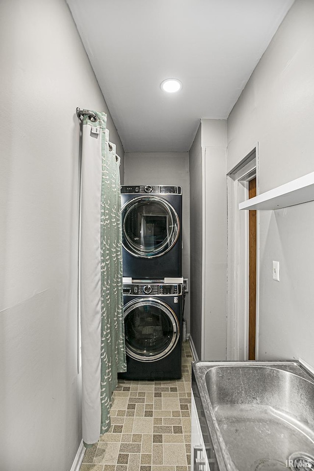 laundry area with stacked washer / drying machine and sink