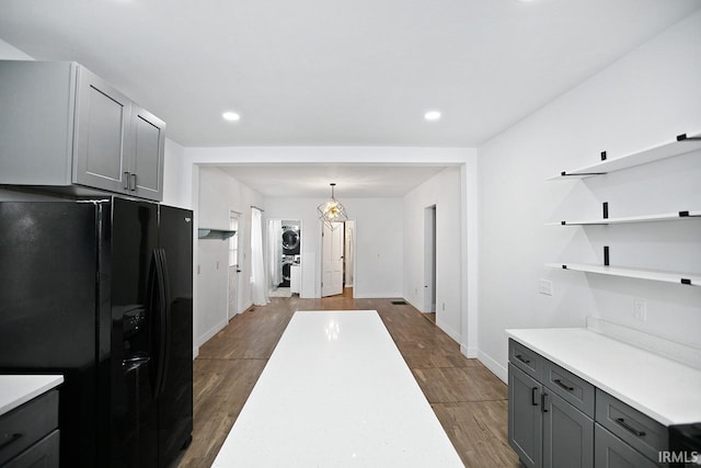 kitchen with dark hardwood / wood-style flooring, black fridge, hanging light fixtures, and gray cabinetry