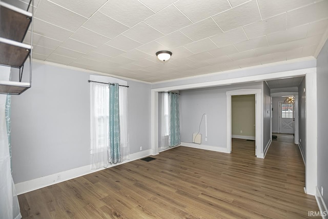 empty room with hardwood / wood-style flooring and crown molding