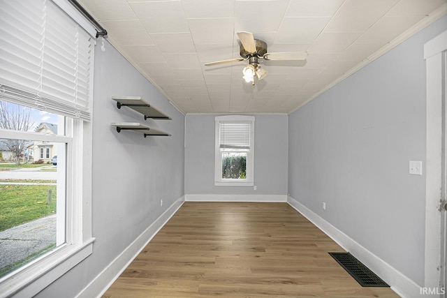 interior space with ceiling fan, light wood-type flooring, ornamental molding, and a wealth of natural light