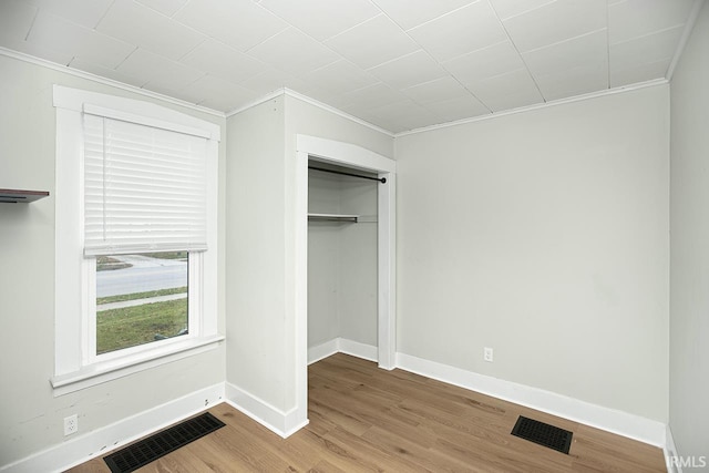 unfurnished bedroom featuring crown molding, a closet, and hardwood / wood-style flooring