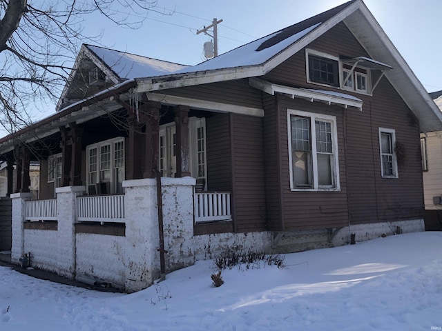 snow covered property with covered porch