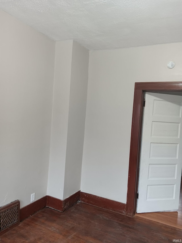 empty room with a textured ceiling and dark wood-type flooring