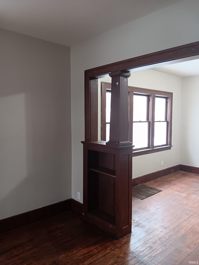 empty room featuring dark hardwood / wood-style flooring and ornate columns