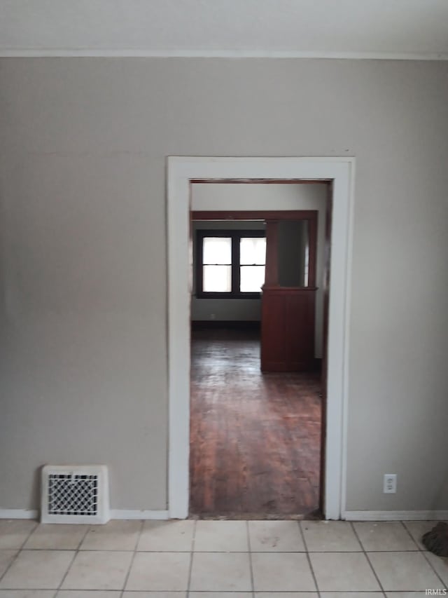 corridor featuring light tile patterned floors and ornamental molding