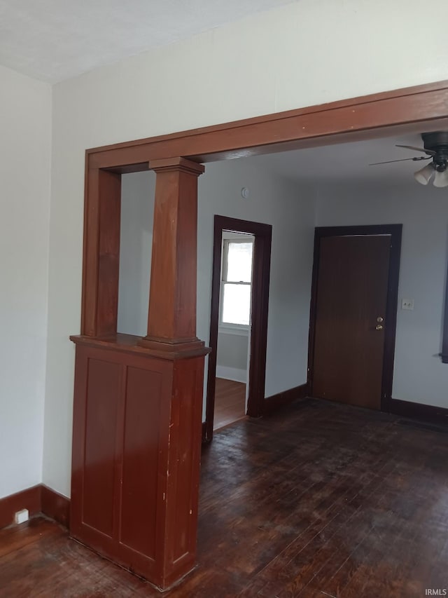 unfurnished room featuring dark hardwood / wood-style flooring, ornate columns, and ceiling fan