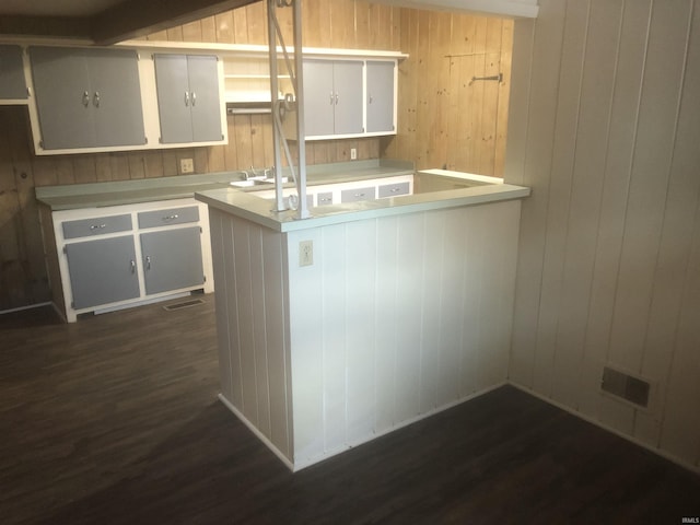 kitchen featuring kitchen peninsula, wood walls, white cabinets, and dark wood-type flooring