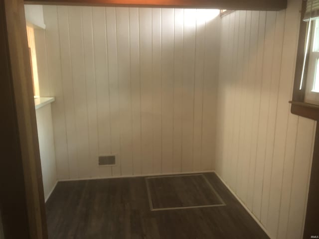 unfurnished room featuring wooden walls and dark hardwood / wood-style flooring