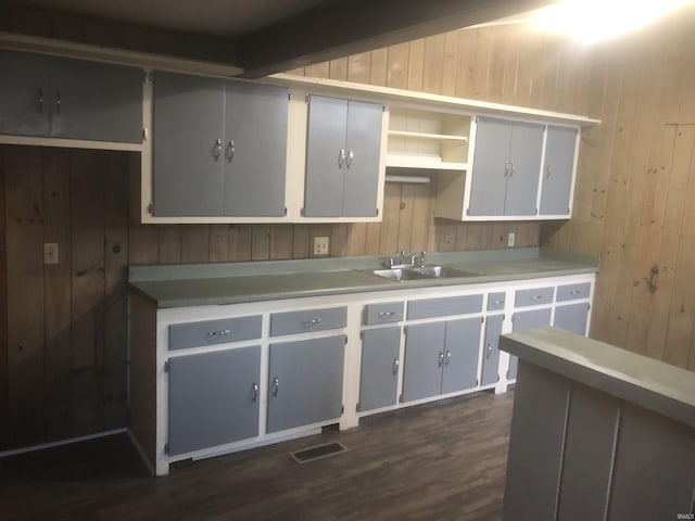 kitchen with gray cabinets, wood walls, and sink